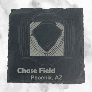 May include: A black slate coaster with a gray outline of Chase Field, a baseball stadium in Phoenix, Arizona. The text "Chase Field" and "Phoenix, AZ" is printed in gray on the coaster.