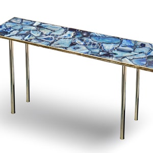 May include: A long, rectangular table with a blue agate top and a gold trim. The table has two chrome legs.