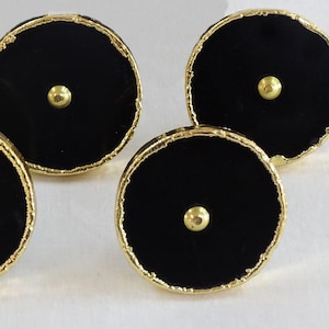 May include: Four round cabinet knobs in black with a gold rim and a raised gold dot in the centre.