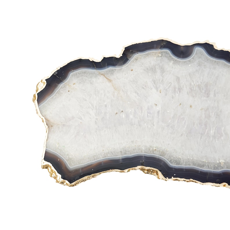 May include: A polished agate slice coaster featuring a translucent white crystalline center surrounded by concentric bands of dark gray and black, finished with a metallic gold-toned electroplated edge along the irregular, organic outer perimeter.