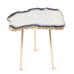 May include: A side table featuring an irregular, geode-inspired tabletop with a white crystalline center, dark gray banding, and a textured gold-tone edge. The table is supported by three slender, polished gold-tone metal legs.