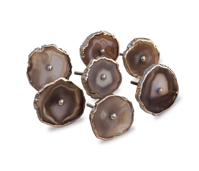 May include: Set of six agate drawer pulls with a gold finish. Each pull features a unique natural agate slice with brown and white patterns.