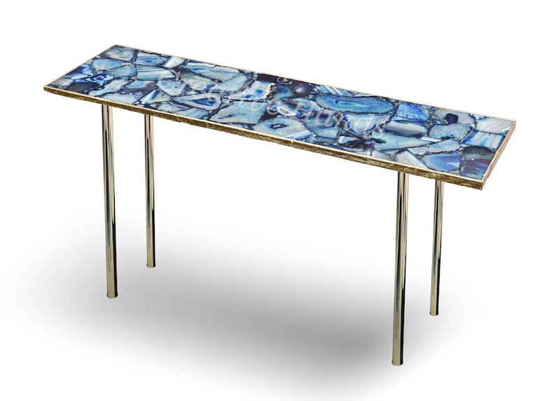 May include: A long, rectangular table with a blue agate top and a gold trim. The table has two chrome legs.