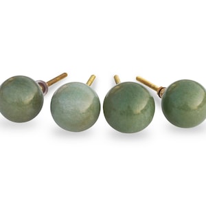May include: Four green ceramic cabinet knobs with gold metal stems. The knobs are round and have a slightly textured surface.