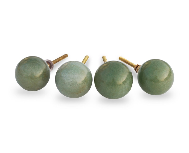 May include: Four green ceramic cabinet knobs with gold metal stems. The knobs are round and have a slightly textured surface.