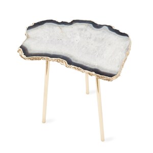 May include: A side table featuring an irregular, slab-like top made of white and translucent agate with a dark gray outer ring and a metallic gold-toned edge. The table is supported by three slender, cylindrical, polished gold-toned metal legs.