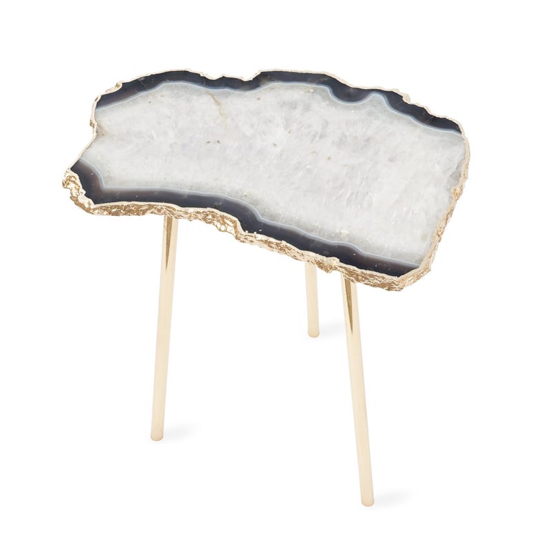 May include: A side table featuring an irregular, slab-like top made of white and translucent agate with a dark gray outer ring and a metallic gold-toned edge. The table is supported by three slender, cylindrical, polished gold-toned metal legs.