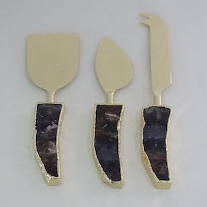 May include: Set of three gold cheese knives with purple and red agate handles.