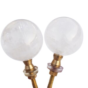 May include: Two clear crystal ball finials with brass bases and screws. The finials are approximately 5 cm in diameter.