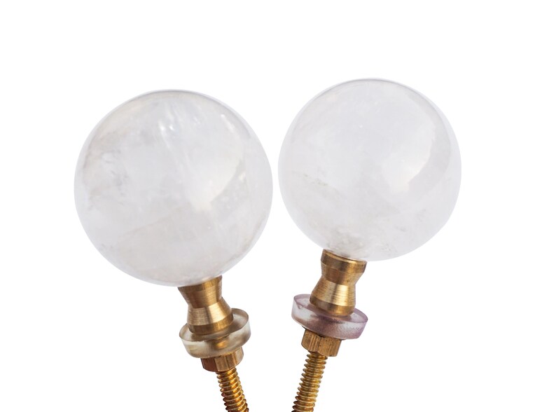 May include: Two clear crystal ball finials with brass bases and screws. The finials are approximately 5 cm in diameter.