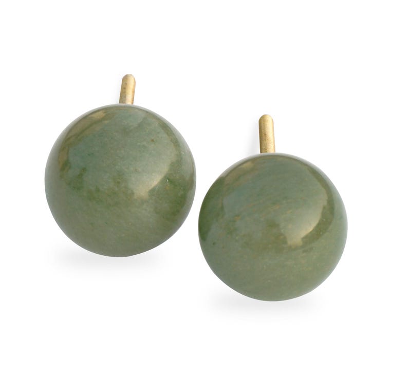 May include: A pair of green jade stone earrings with gold posts. The earrings are round and have a smooth, polished finish.