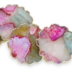 Puede incluir: Tres posavasos de &aacute;gata con ribete dorado. Los posavasos son redondos y tienen una combinaci&oacute;n de colores rosa, blanco y verde.