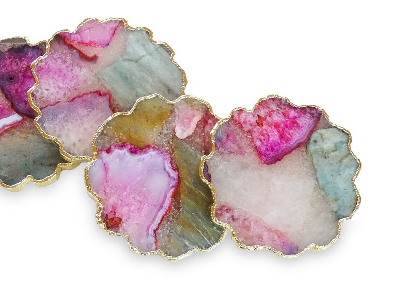Puede incluir: Tres posavasos de &aacute;gata con ribete dorado. Los posavasos son redondos y tienen una combinaci&oacute;n de colores rosa, blanco y verde.