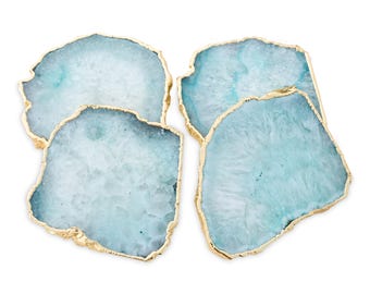 May include: A set of four irregular, slab-shaped coasters made of translucent light blue agate stone. Each coaster features a natural crystalline texture and is finished with a metallic gold-colored electroplated edge along the entire perimeter.