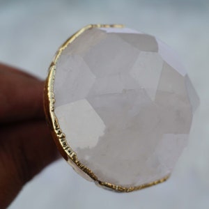May include: A large, faceted, white quartz crystal ring with a gold-toned metal setting.