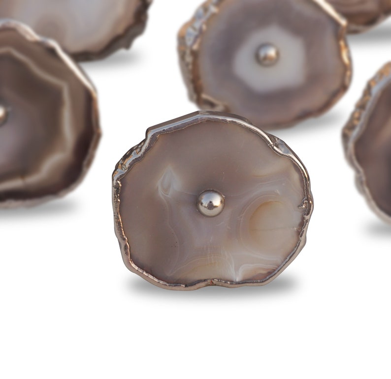 May include: A set of six agate drawer pulls with a silver metal trim. Each pull features a unique natural agate pattern in shades of gray and white.