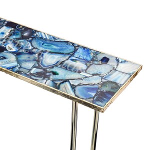May include: A blue agate console table with a gold trim and two metal legs. The table top is made of a mosaic of blue agate stones.
