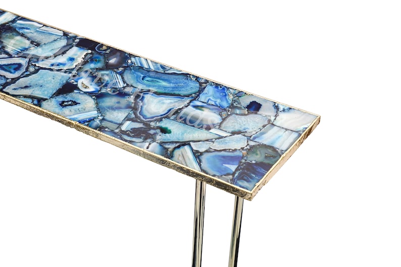 May include: A blue agate console table with a gold trim and two metal legs. The table top is made of a mosaic of blue agate stones.