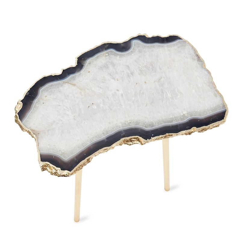 May include: A side table featuring an irregular, slab-like top made of white and dark gray agate stone with a natural, rough-hewn edge finished in metallic gold. The tabletop is supported by two slender, cylindrical legs in a matching gold tone.
