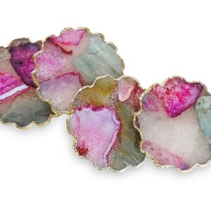 Puede incluir: Tres posavasos de &aacute;gata con ribete dorado. Los posavasos son de color rosa, verde y blanco con un patr&oacute;n natural y org&aacute;nico.