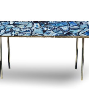 May include: A blue agate coffee table with a gold trim and chrome legs. The table top is made of natural agate stone and has a unique pattern.