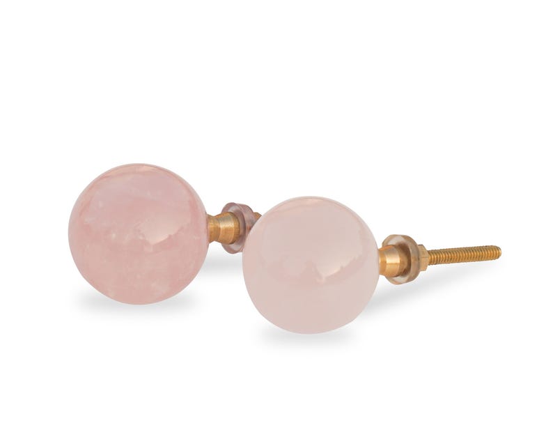 Pu&ograve; includere: Due pomelli rotondi rosa con ferramenta in metallo dorato. I pomelli sono in quarzo rosa e hanno una finitura liscia e lucida.