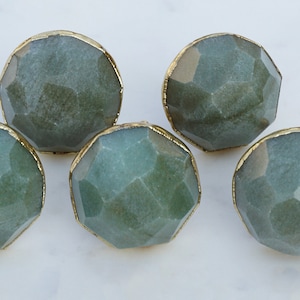 Könnte beinhalten: Fünf grüne und goldene Edelsteinknauf für Schränke mit facettiertem Design.