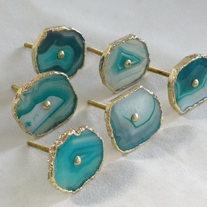 May include: Six agate drawer pulls with gold trim. The agate is a mix of teal, white, and green.