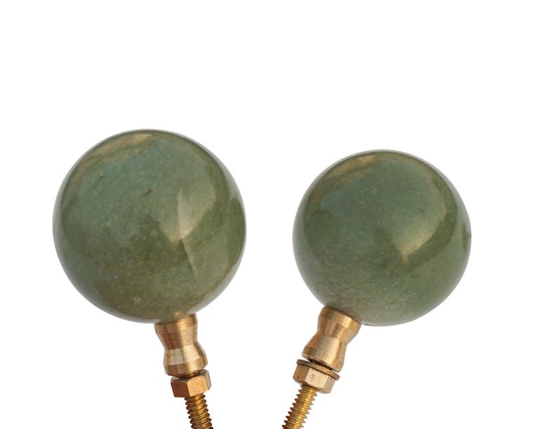 May include: Two green ceramic finials with brass bases. The finials are round and have a smooth, slightly textured surface.