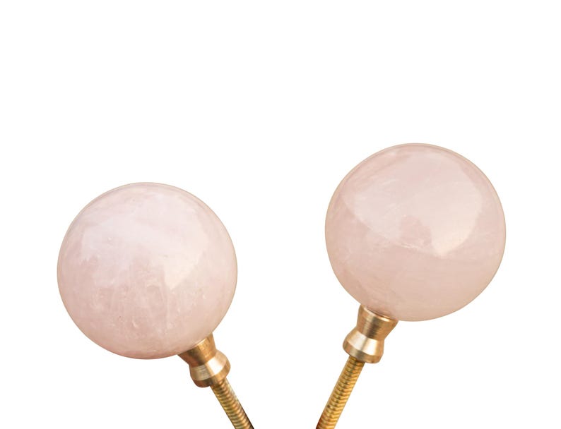 Pu&ograve; includere: Due pomelli rotondi in quarzo rosa rosa con basi in metallo dorato. I pomelli sono lisci e lucidi.