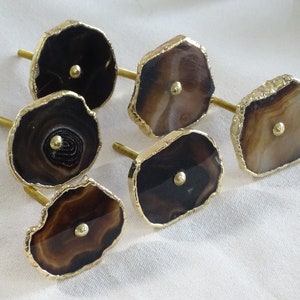 以下が含まれることがあります： 金色の縁取りが施された茶色の瑪瑙製の引き出しノブが6つ。各ノブの中央には小さな金色のノブがあります。