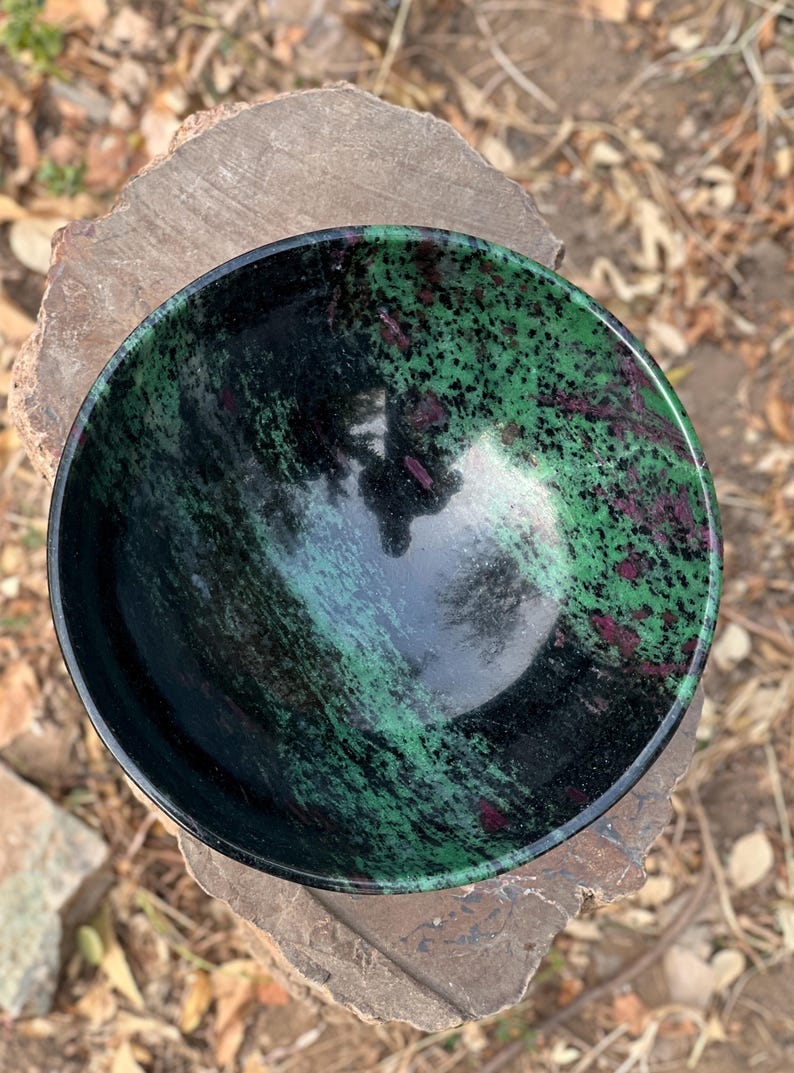 May include: A green and black bowl made of polished stone. The bowl has a swirling pattern of green and black with hints of pink.
