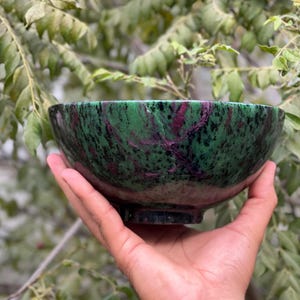May include: A green and pink bowl made of polished stone. The bowl has a swirling pattern of green, pink, and black.