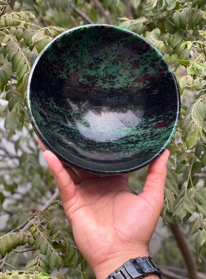 May include: A green and black bowl made of polished stone. The bowl has a swirling pattern of green and black with hints of pink.