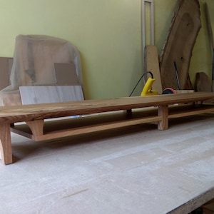 Puede incluir: Una estanter&iacute;a larga de madera con dos niveles. La estanter&iacute;a est&aacute; hecha de madera natural con un acabado r&uacute;stico. La estanter&iacute;a est&aacute; soportada por cuatro patas y tiene un borde ligeramente curvado.