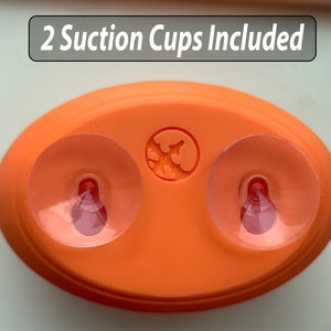 May include: Orange oval-shaped suction cup holder with two clear suction cups and the text "2 Suction Cups Included".