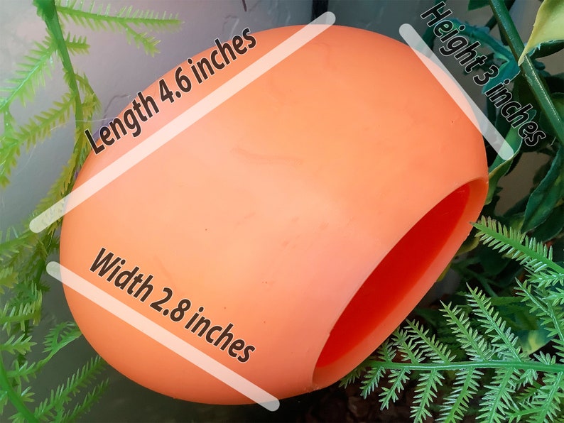 May include: A bright orange, hollow, plastic egg-shaped object with a large opening on one side. The object measures 4.6 inches in length, 2.8 inches in width, and 3 inches in height.