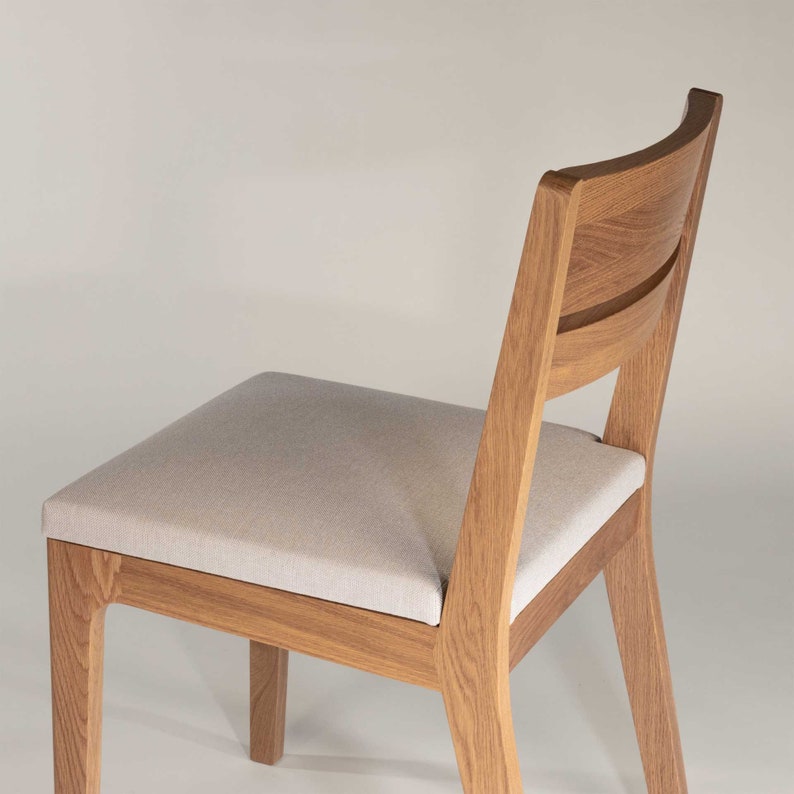 May include: A wooden chair with a light gray fabric seat. The chair has a curved back and a simple design.