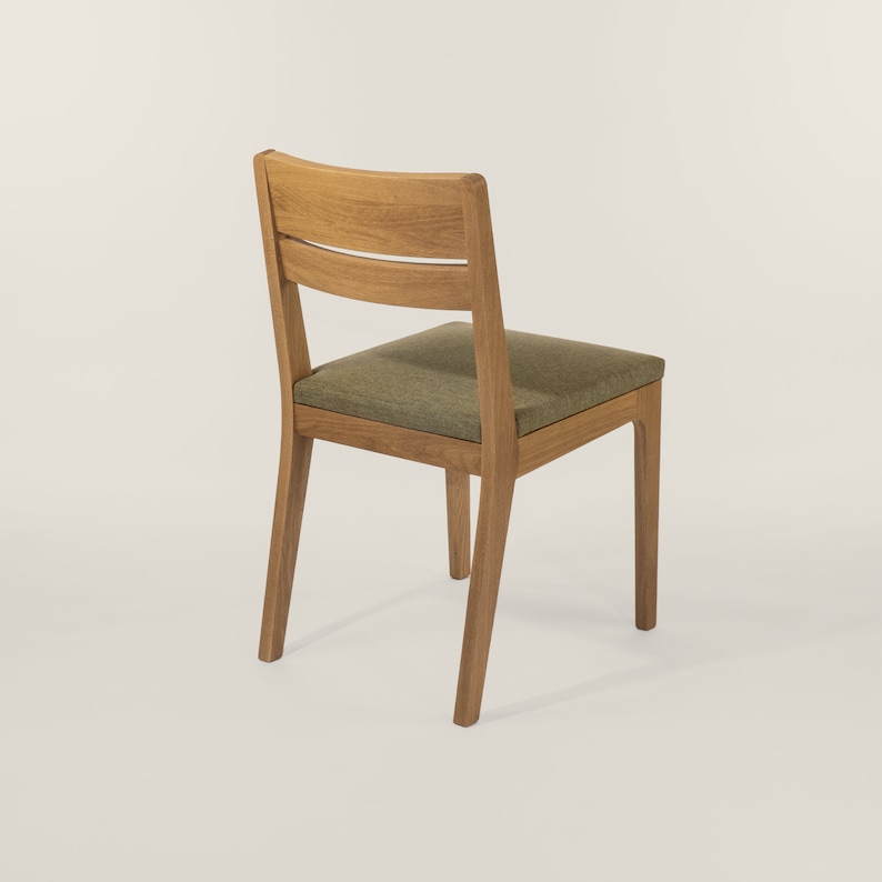 May include: A wooden chair with a green upholstered seat and a simple, straight-backed design.