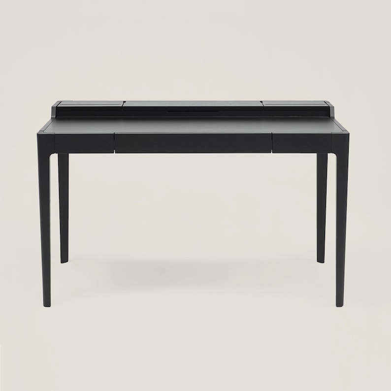 May include: A black desk with a rectangular top and four legs. The desk has a drawer on each side and a small compartment on the top.