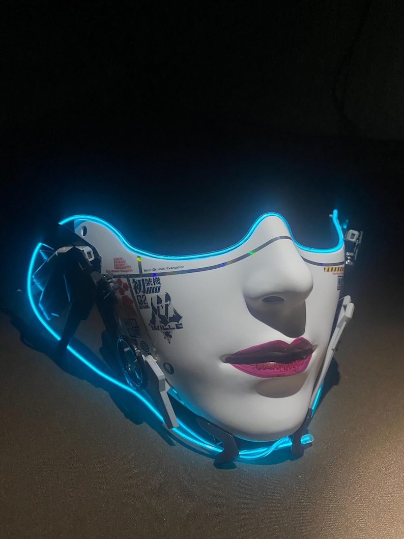 May include: A white face mask with a feminine design, featuring pink lips and a blue neon outline. The mask has Japanese text and mechanical details, creating a futuristic aesthetic.