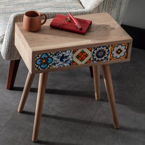 May include: A wooden side table with a decorative tile design on the front. The table has four legs and a rectangular top.