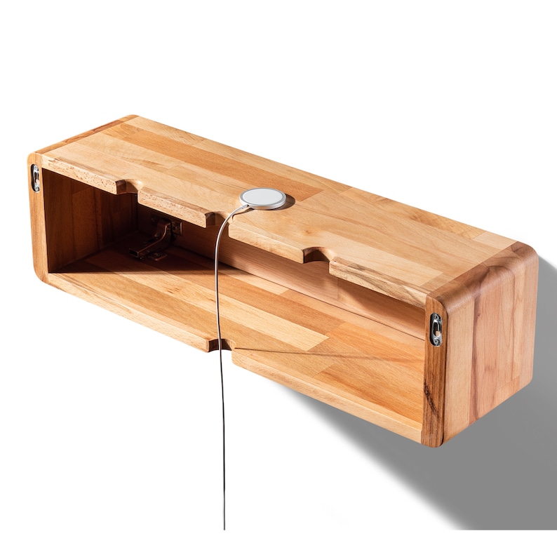 May include: A wooden wall-mounted shelf with a hidden compartment and a wireless charging pad on top. The shelf is made of light wood with a natural finish.
