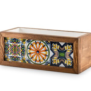 May include: Rectangular wooden planter box with a dark brown finish. The front features three decorative ceramic tiles with colorful floral and geometric patterns. The interior is lined with white material.