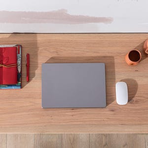 Pu&ograve; includere: Una scrivania in legno con un computer portatile, un mouse, una penna, una pila di quaderni e due pezzi di terracotta.