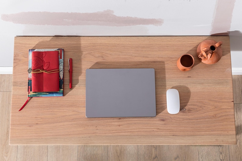 Pu&ograve; includere: Una scrivania in legno con un computer portatile, un mouse, una penna, una pila di quaderni e due pezzi di terracotta.