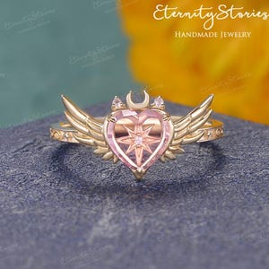 Anello di fidanzamento con zaffiro rosa a forma di cuore e ali d'angelo, gioielli fantasy con luna e stelle, regalo kawaii per ragazze magiche. immagine 1