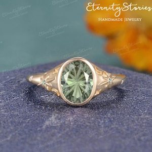 May include: A gold-coloured ring with an oval, light green gemstone. The ring has star and crescent moon designs on the sides. The words "Eternity Stories Handmade Jewelry" are in the background.