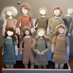 May include: A group of ten handmade fabric dolls with different hair colours and clothing. The dolls are standing on a wooden shelf with a blue painted surface.