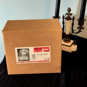 Könnte beinhalten: Ein Set aus drei Keramikbechern mit gesprenkelter, cremefarbener Glasur. Jeder Becher zeigt ein handgemaltes Blumendesign in Blau-, Grün- und Gelbtönen. Die Becher haben eine einfache, abgerundete Form und einen bequemen Griff.